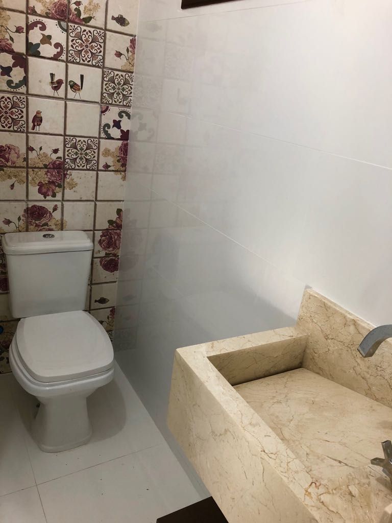 Casa de banho com sanita, lavatório e azulejos decorativos.