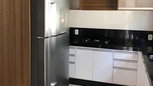 A modern kitchen with a stainless steel refrigerator, white cabinets, and a black countertop.