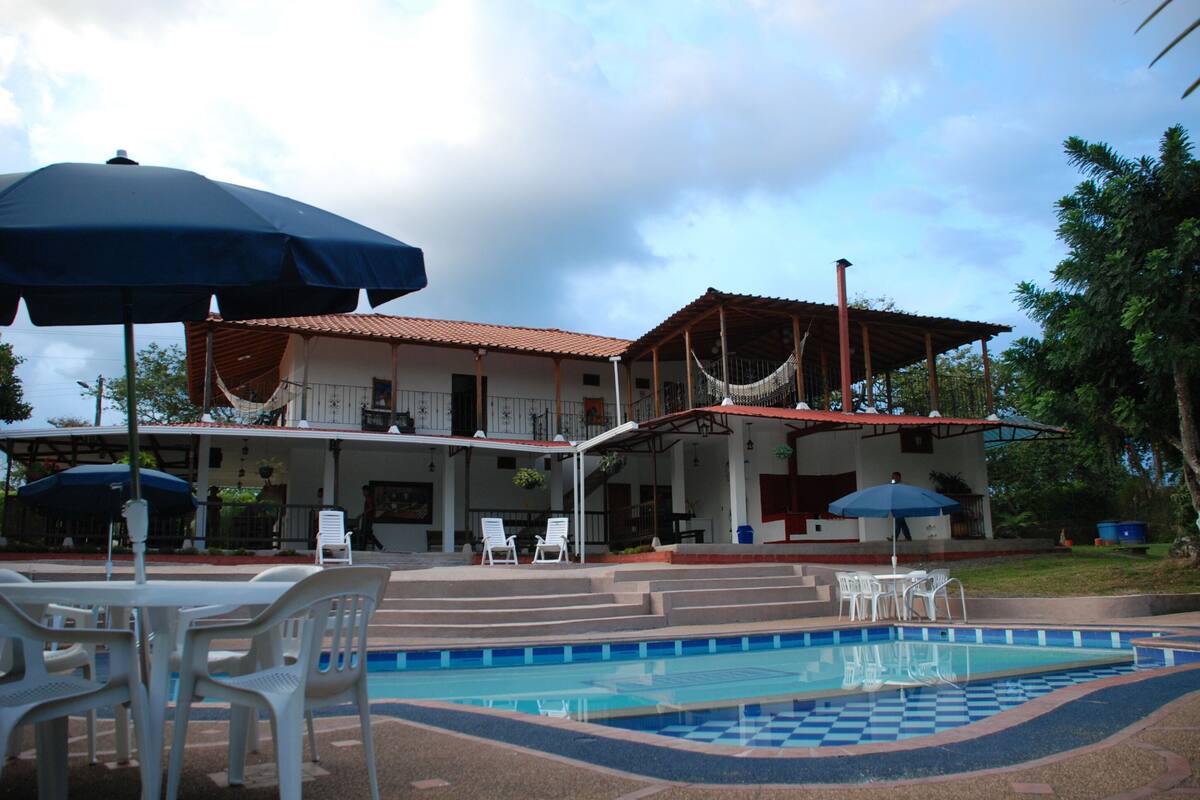 A pool area with a checkered pattern, white chairs, and umbrellas.