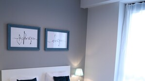 A neatly made bed with a floral-patterned bedspread, two framed artworks on the wall, and a bedside lamp. - -30% off  Natalité Houzz Tbilisi (Tbilisi)