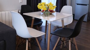A modern living room with a dining table, two white chairs, and a black chair. There is a vase with yellow flowers on the table. - -30% off  Natalité Houzz Tbilisi (Tbilisi)