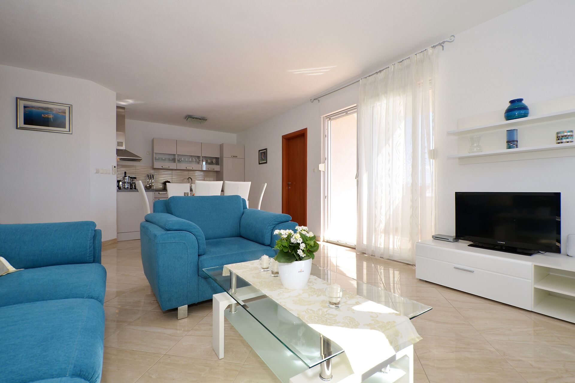 Ein modernes Wohnzimmer mit einem blauen Sofa, einem Glastisch und einem Flachbildfernseher.