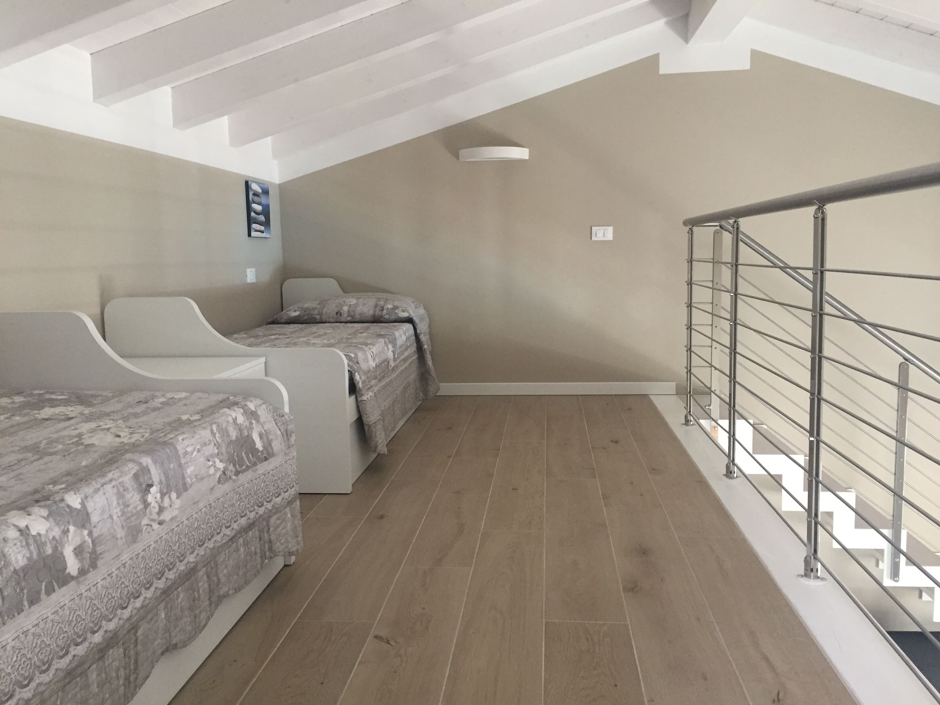 Une chambre avec deux lits, un escalier et une rambarde.
