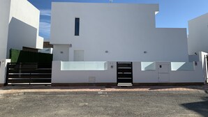 Un edificio moderno con fachada plana, una ventana pequeña y una puerta con un cartel que indica la habitación 2C.