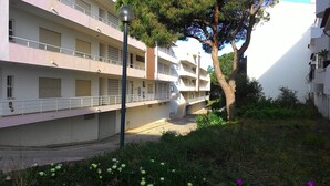 Un immeuble résidentiel à plusieurs étages, doté de balcons, d’un chemin pavé et d’un arbre.