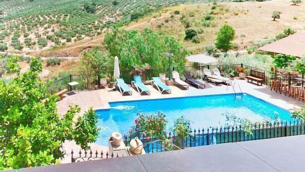 A pool area with lounge chairs and a view of a hilly landscape.