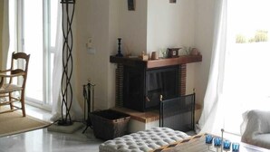 Ein Wohnzimmer mit Deckenventilator, Kamin, Sofa, Couchtisch und einem Fenster mit Vorhängen.
