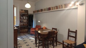 Un comedor con una mesa y sillas de madera, una estantería llena de libros y una lámpara.