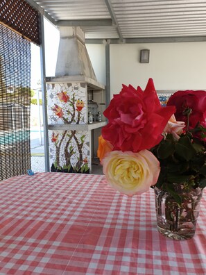 Una mesa con mantel a cuadros, un jarrón con flores y una pared de azulejos con diseño de mosaico.