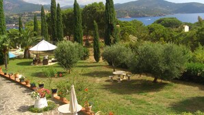 A garden with a gazebo, stone pathway, and outdoor seating area overlooking a lake and mountains. - Vista Mare with private pool, large 65,000 square meter garden, sea view, close to the beach.  (Capoliveri)