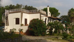 A white villa with a balcony, a staircase, and a garden with various plants and flowers. - Vista Mare with private pool, large 65,000 square meter garden, sea view, close to the beach.  (Capoliveri)