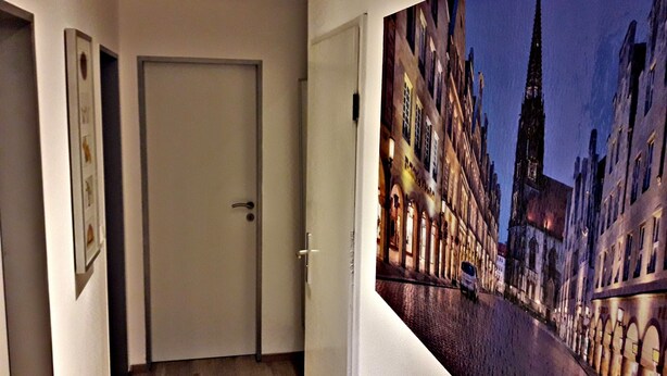 Un pasillo con una puerta y un cartel grande de un paisaje urbano europeo de noche.