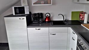 Una cocina moderna con microondas, cafetera, hervidor y lavabo.