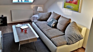 Una sala de estar moderna con un sofá, una mesa de centro, una lámpara y un cuadro en la pared.
