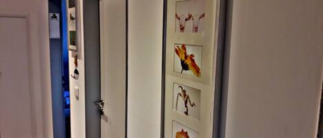A hallway with a door leading to a room, a framed picture of a cow, and a framed picture of a flower.