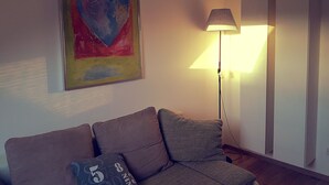 Un salón con sofá, lámpara y un cuadro de un corazón.