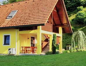 A yellow building with a red-tiled roof, a wooden staircase, and a small window.