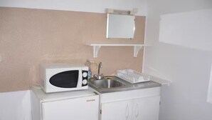 A compact kitchenette with a microwave, sink, and white cabinets. - Large detached comfortable room (Le Mesnil-Esnard)