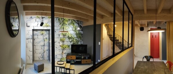Una sala moderna con pared de piedra, televisor de pantalla plana y comedor con mesa y sillas.