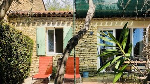 A stone building with a green awning, two red chairs outside, and a number '26' sign. - Charming Bastidon with Terrace, Garden, and Pool in Gordes, Luberon  (Gordes)