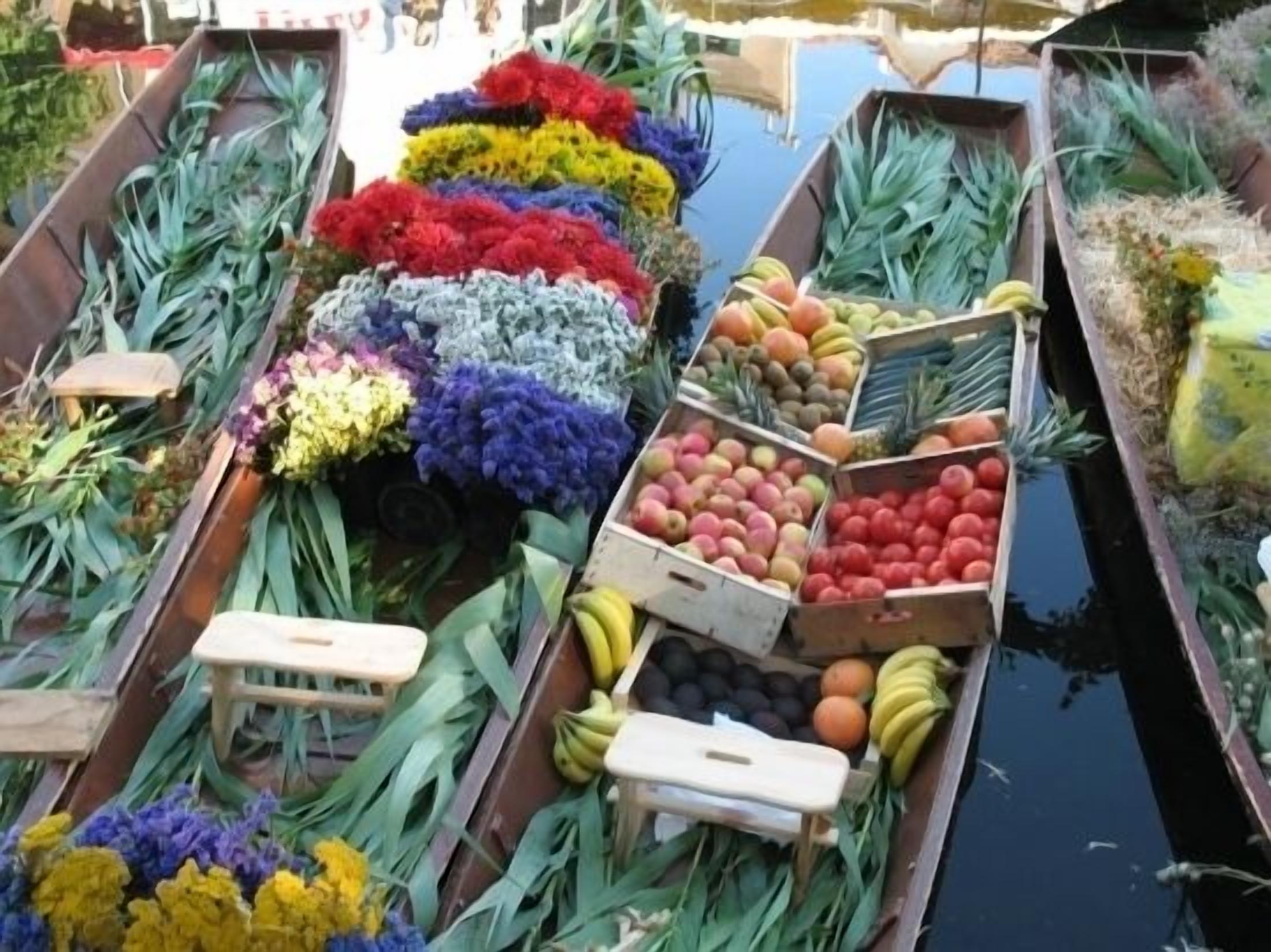 A floating market with boats filled with colorful flowers and fruits.