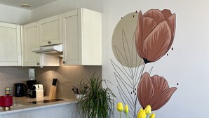 A modern kitchen with white cabinets, a wooden countertop, and a dining table with a vase of yellow tulips. - Charming Bastidon with Terrace, Garden, and Pool in Gordes, Luberon  (Gordes)