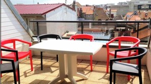 Enjoy the city view from this balcony with a table and chairs.