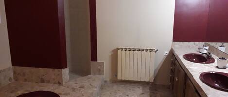 A bathroom with two sinks, a shower, and a radiator.