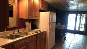 A kitchen with wooden cabinets, a white refrigerator, a sink, and a window with a view of the outdoors. - Luxury Lakefront Living in Lake Sebago Area (Bridgton)