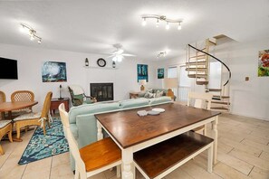 Un vaste espace de vie comprenant une table à manger, un canapé et un escalier.