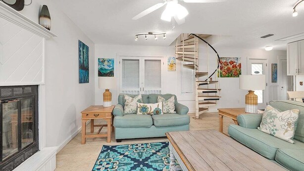 A living room with a fireplace, a sofa, a coffee table, and a spiral staircase.