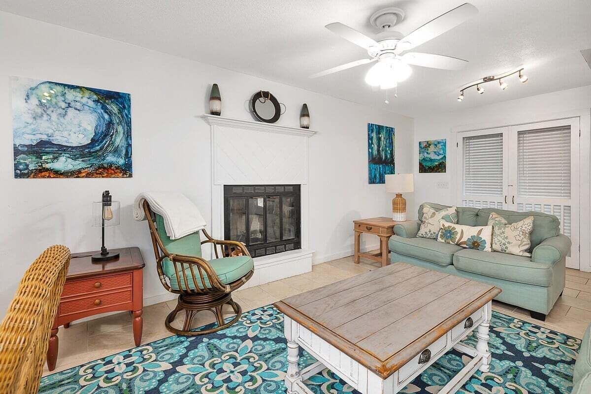 A living room with a fireplace, a sofa, a coffee table, and a ceiling fan.