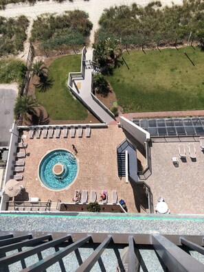 Un área de piscina en la azotea con piscina circular, sillas de descanso y una escalera que conduce al nivel superior.