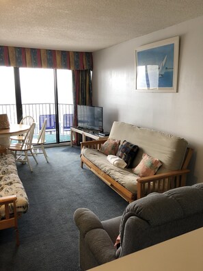 Relax in the spacious living area with a sofa, TV, dining table, and balcony with a view.