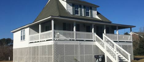 A two-story house with a porch and a staircase leading to the upper level.