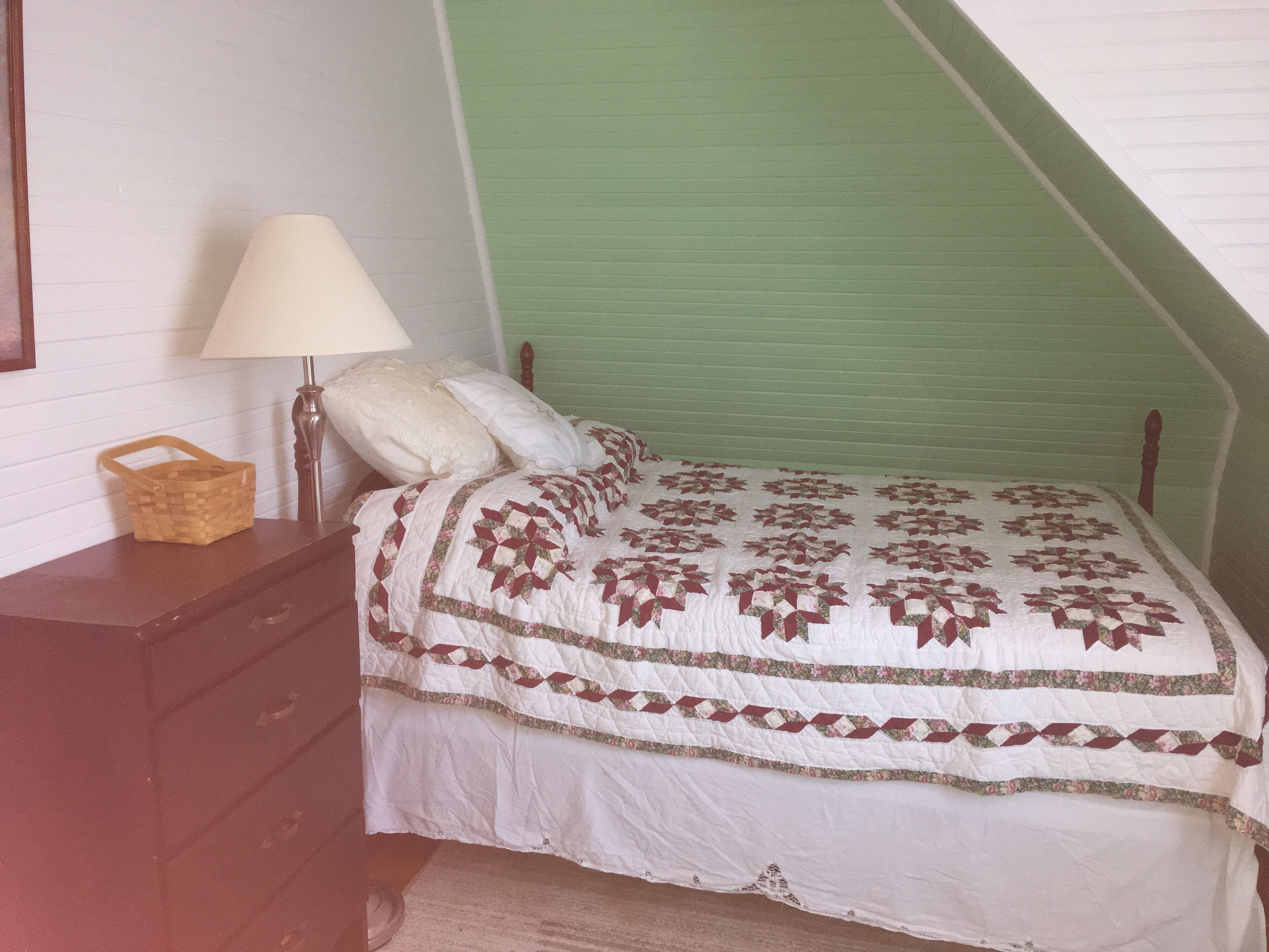 A bedroom with a bed, a nightstand, a lamp, and a basket.