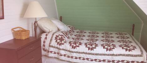 A bedroom with a bed, a nightstand, a lamp, and a basket.