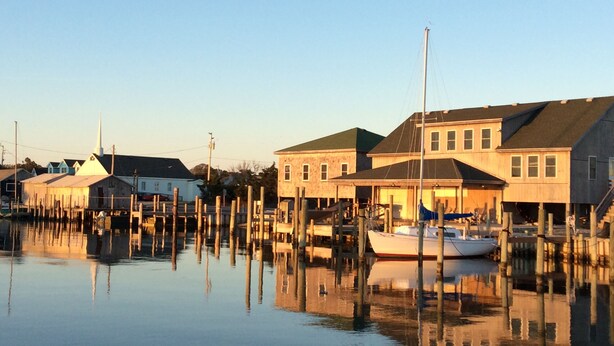 A waterfront property with multiple buildings, docked boats, and a calm water body reflecting the structures.