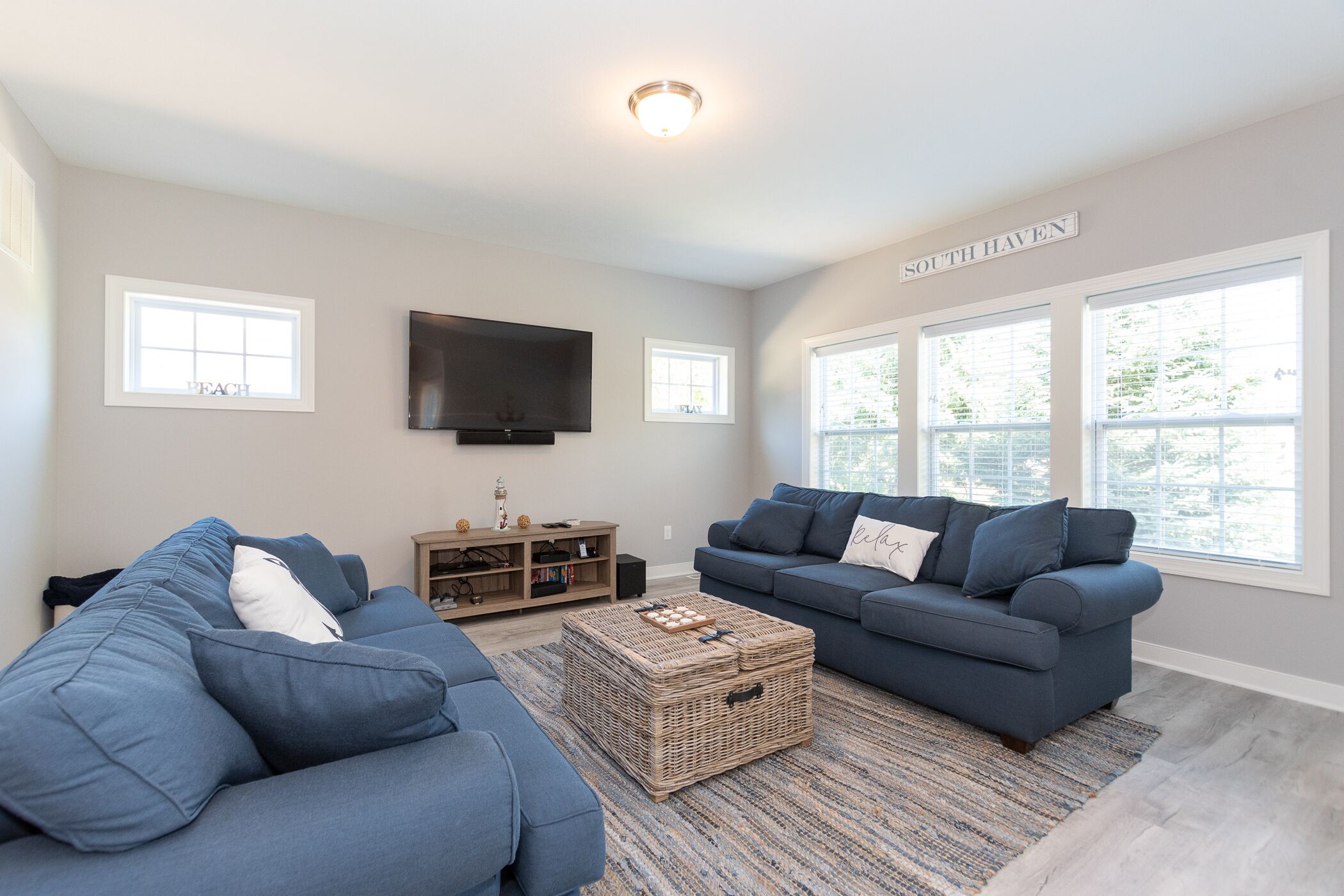 A living room with two blue sofas, a television, and a large window labeled "SOUTH HAVEN".