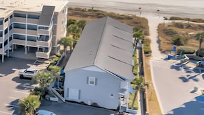 A beachfront hotel with a parking lot, a building with a flat roof, and a view of the ocean. - Steps away from beach. Great for families. Townhouse with 3 bedrooms & 3 baths.  (North Myrtle Beach)