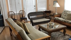 Un salon comprenant un canapé, deux fauteuils, une table basse et une lampe.
