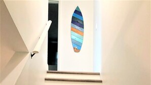 A staircase with wooden steps and a wall-mounted surfboard decoration. - Beach Cottage, Steps to Beach. Updated and Great Deal for Money. Pet Friendly. (Fort Pierce)