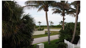 A residential area with palm trees, a white fence, and a road. - Beach Cottage, Steps to Beach. Updated and Great Deal for Money. Pet Friendly. (Fort Pierce)