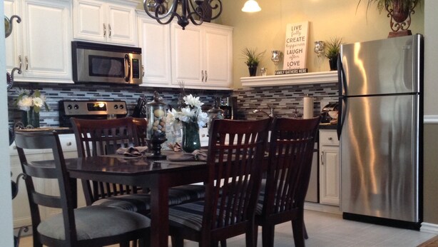 A modern kitchen with white cabinets, a stainless steel refrigerator, and a dining table with chairs. - Amazing 5 Star Home, Amenities Galore, AC, no pet fee, 7 miles to NAU (Flagstaff)