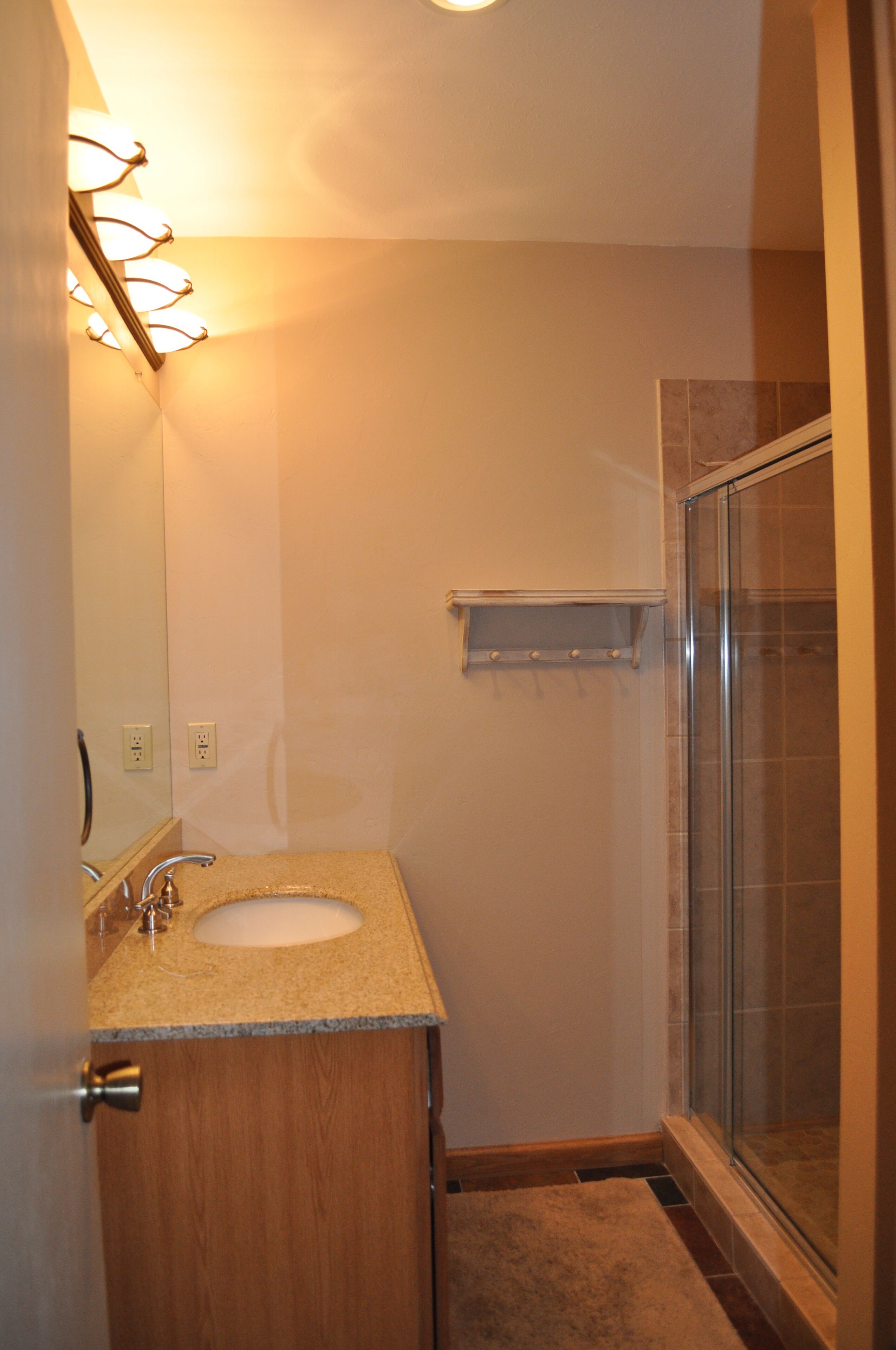 A bathroom with a sink, mirror, and shower.