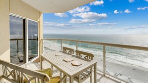 Een balkon met uitzicht op de oceaan, een houten tafel en een stoel.