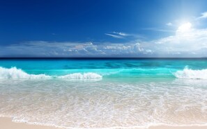 Une plage à l’eau turquoise et limpide et au sable blanc.