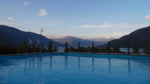 A swimming pool with a view of mountains and a lake. - Hotel Giardino (Cannobio)
