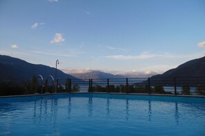 Una piscina con vistas a montañas y un lago.