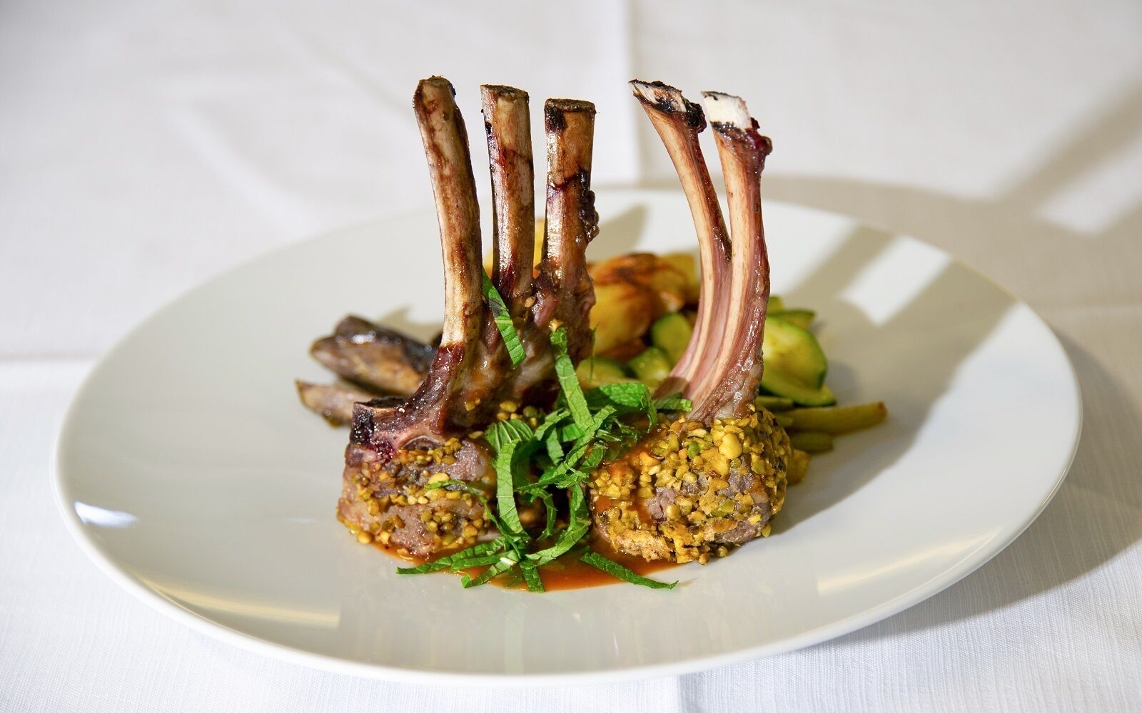 A plate of food with lamb chops and a side of vegetables.